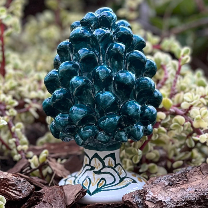 Decorative green ceramic hand painted pine cone on a natural background