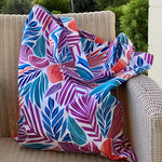 Colorful Drifting Leaf patterned waterproof tote bag draped over a wicker chair outdoors.