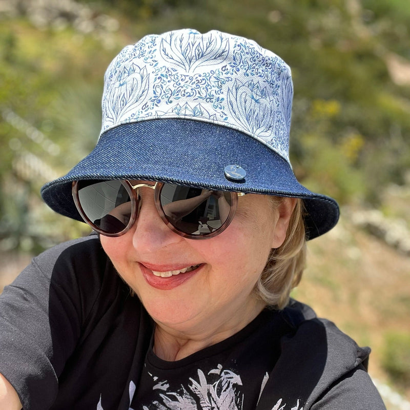 Person wearing a bucket hat with blue and white bird of paradise patterned fabric trimmed in denim.