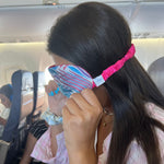 Woman sitting on an airplane wearing a colorful eye mask from Bdesign’s Drifting Leaves collection, designed for comfortable sleep during travel.