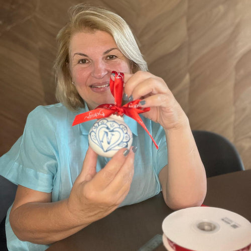 Woman holding a decorative ornament with red ribbon in an indoor setting